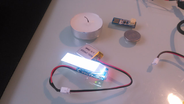Adafruit Trinket with a backlight module attached, alongside a tealight